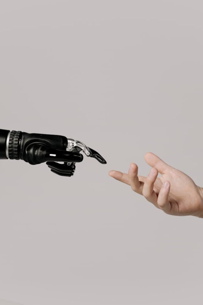 pexels-photo-6153343 A human hand reaching to touch a bionic prosthetic hand on a white background.